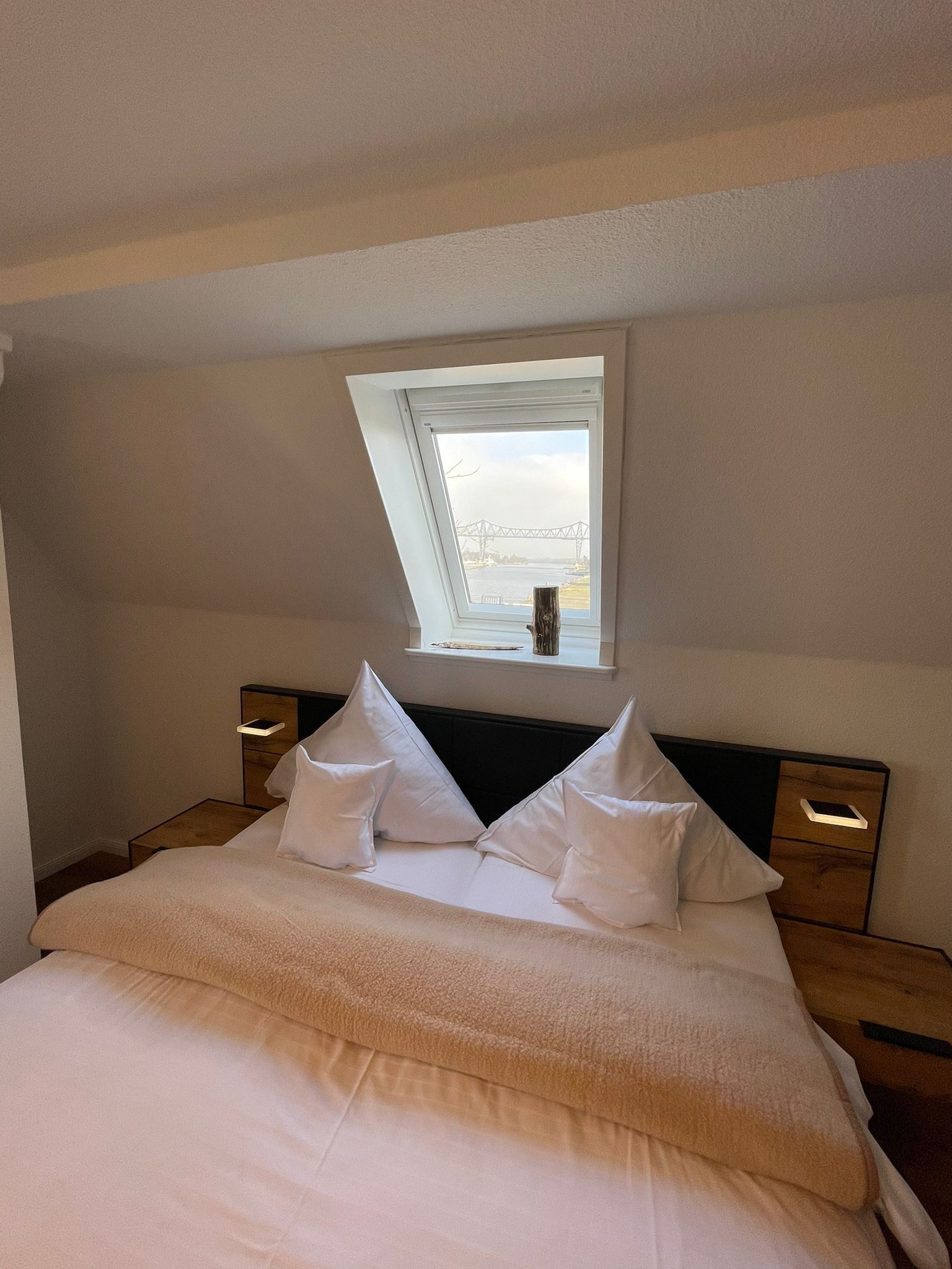 A bedroom with a skylight, a bed with white bedding, and two bedside tables.
