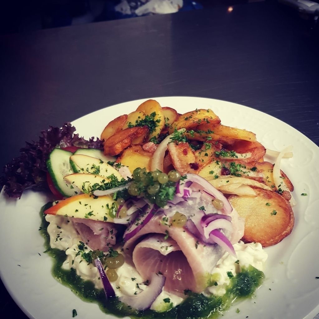 Un plato de comida con papas, cebollas y verduras.