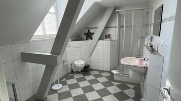A modern bathroom with a checkered floor, a toilet, a sink, and a shower.
