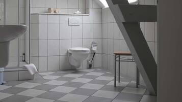 Un baño con piso a cuadros, inodoro, lavamanos y zona de ducha.