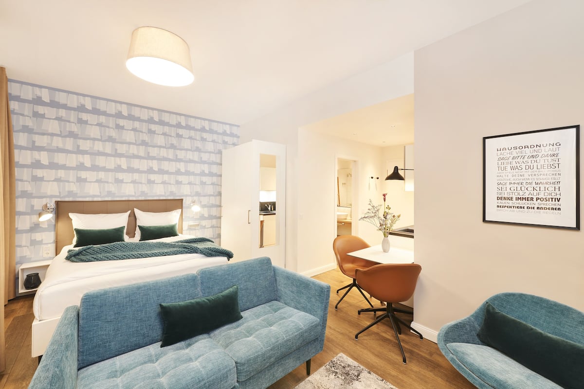 Un dormitorio moderno con una cama grande, un sofá azul y un comedor con mesa y sillas.