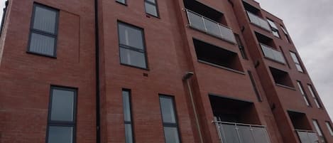A multi-story brick building with balconies and large windows.