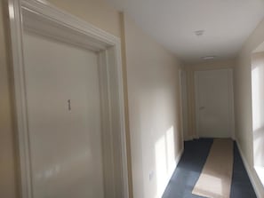 A narrow hallway with a carpeted floor and white walls. - Jaylets Premier Apartments, Leicester. (Leicester)