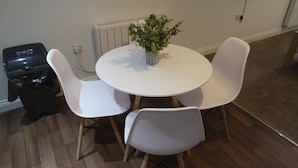 A small dining area with a round white table and four white chairs. A potted plant is on the table. - Jaylets Premier Apartments, Leicester. (Leicester)