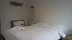 A neatly made bed with white linens and a wooden headboard. - Jaylets Premier Apartments, Leicester. (Leicester)