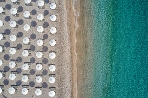 Rannalla, mustaa hiekkaa, ilmaiset rantakuljetukset, aurinkotuoleja