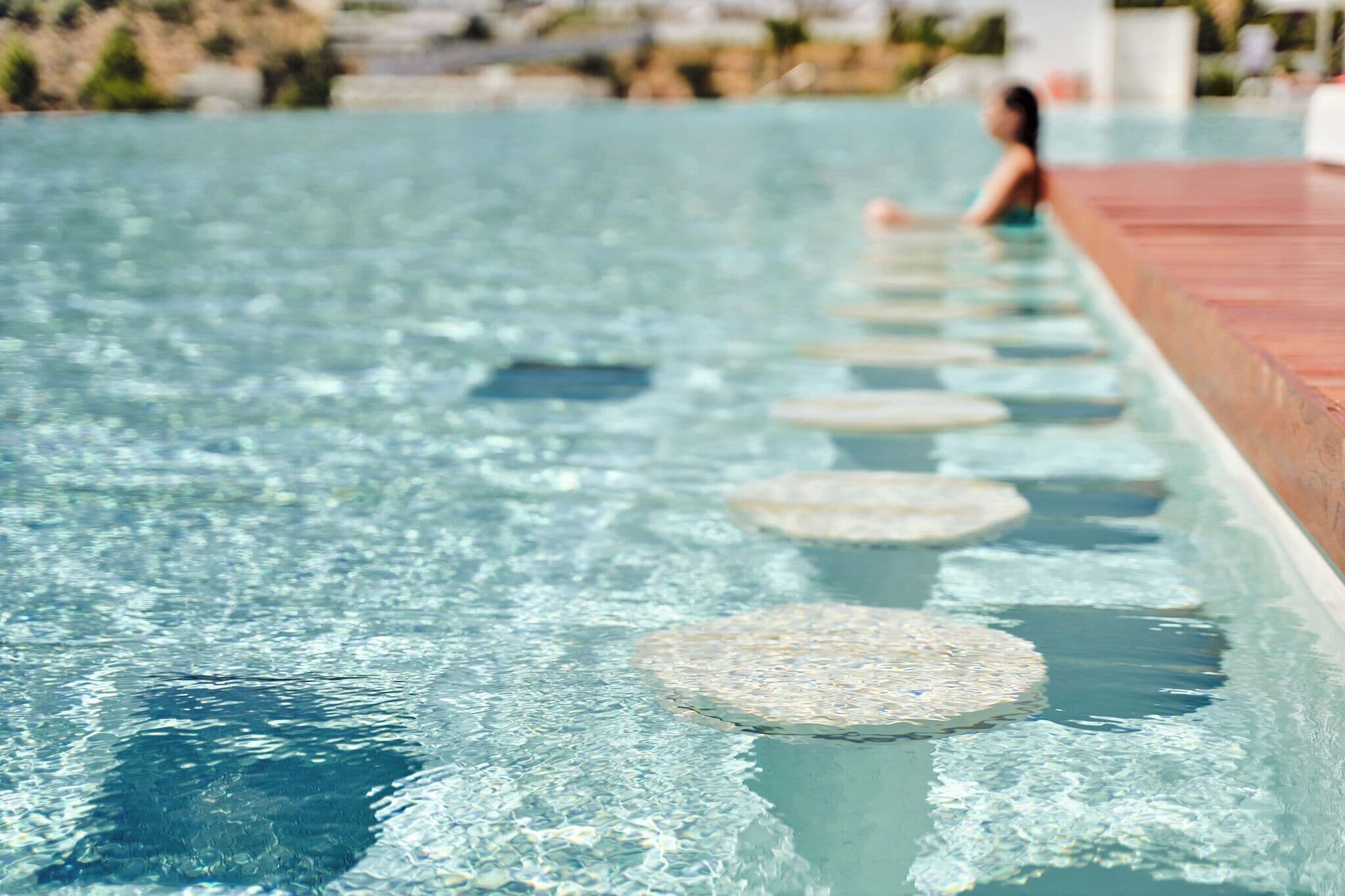 A swimming pool with clear water and circular stepping stones.