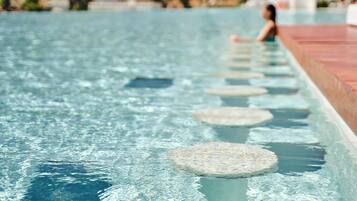 A swimming pool with clear water and circular stepping stones.
