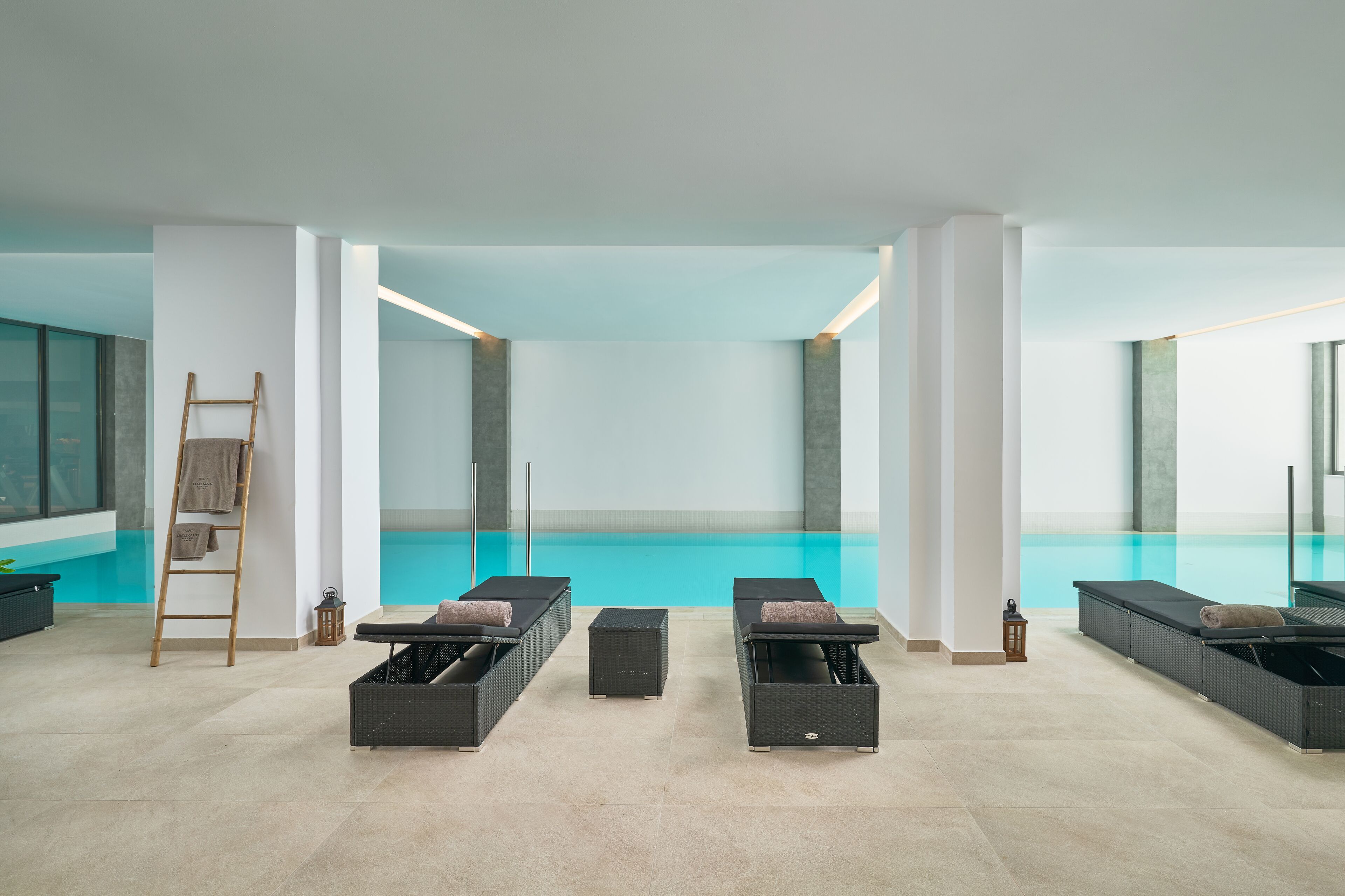 Un'area piscina interna moderna con sedie a sdraio e una scala.