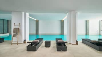 Un'area piscina interna moderna con sedie a sdraio e una scala.