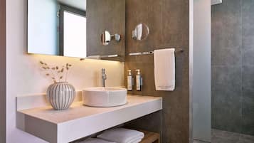 A modern bathroom with a white sink, a large mirror, and a towel rack.