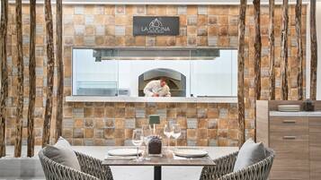 A restaurant with a stone wall, wooden beams, and a pizza oven.