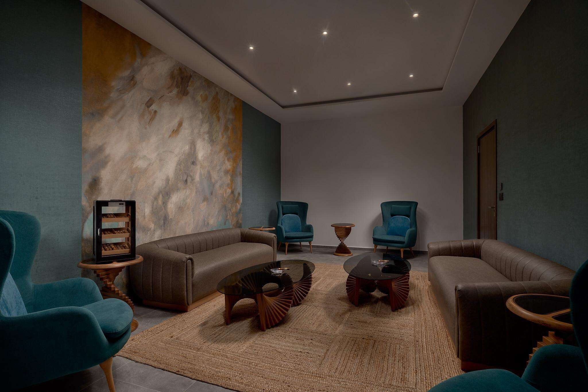 Een moderne woonkamer met een grote abstracte muurschildering, twee banken, een salontafel en een bijzettafeltje met een ingelijste foto.