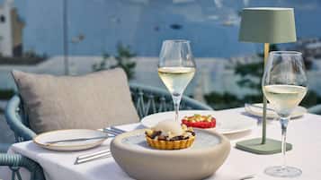 A table set with a dessert bowl, two glasses of white wine, and a lamp.