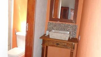 Un baño con inodoro, lavamanos con espejo y piso de baldosas.