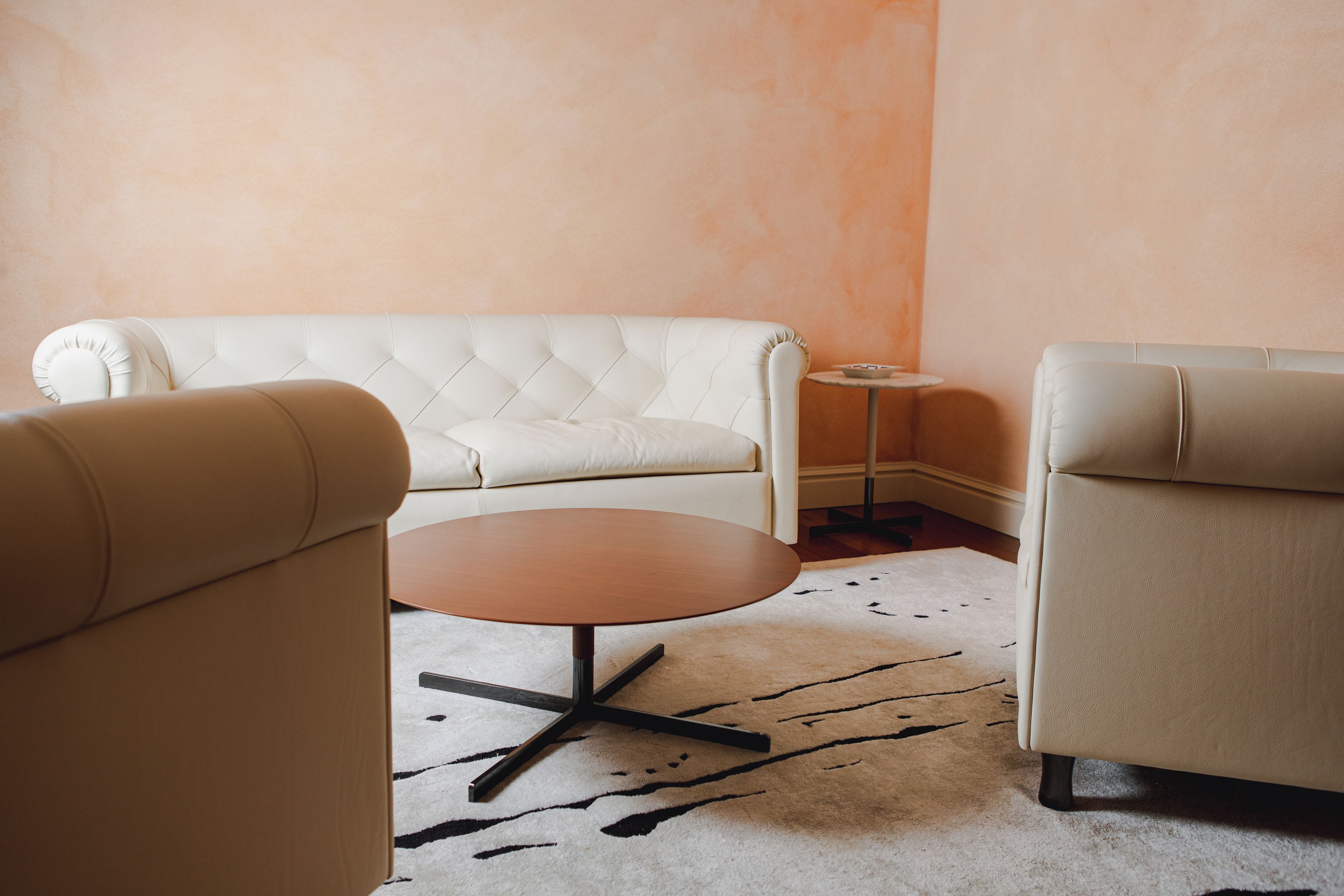 Una habitación con un sofá blanco, una mesa redonda de centro y una mesita auxiliar.