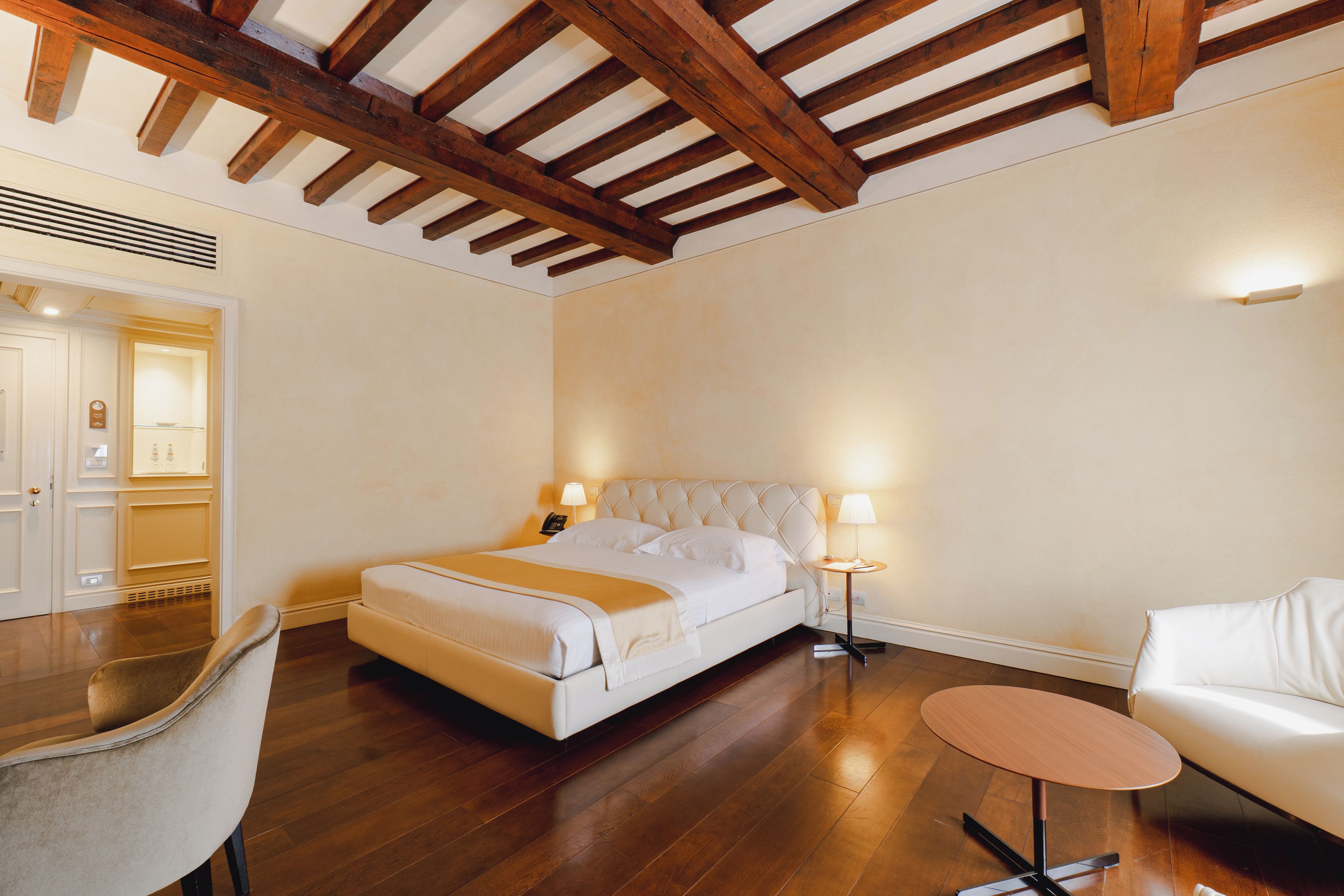 A hotel room with a bed, bedside tables, a chair, and a small table.