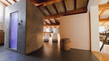 A modern interior with a concrete accent wall, a wooden ceiling, and a seating area with a small trash bin.