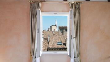A room with a window, curtains, and a view of buildings.