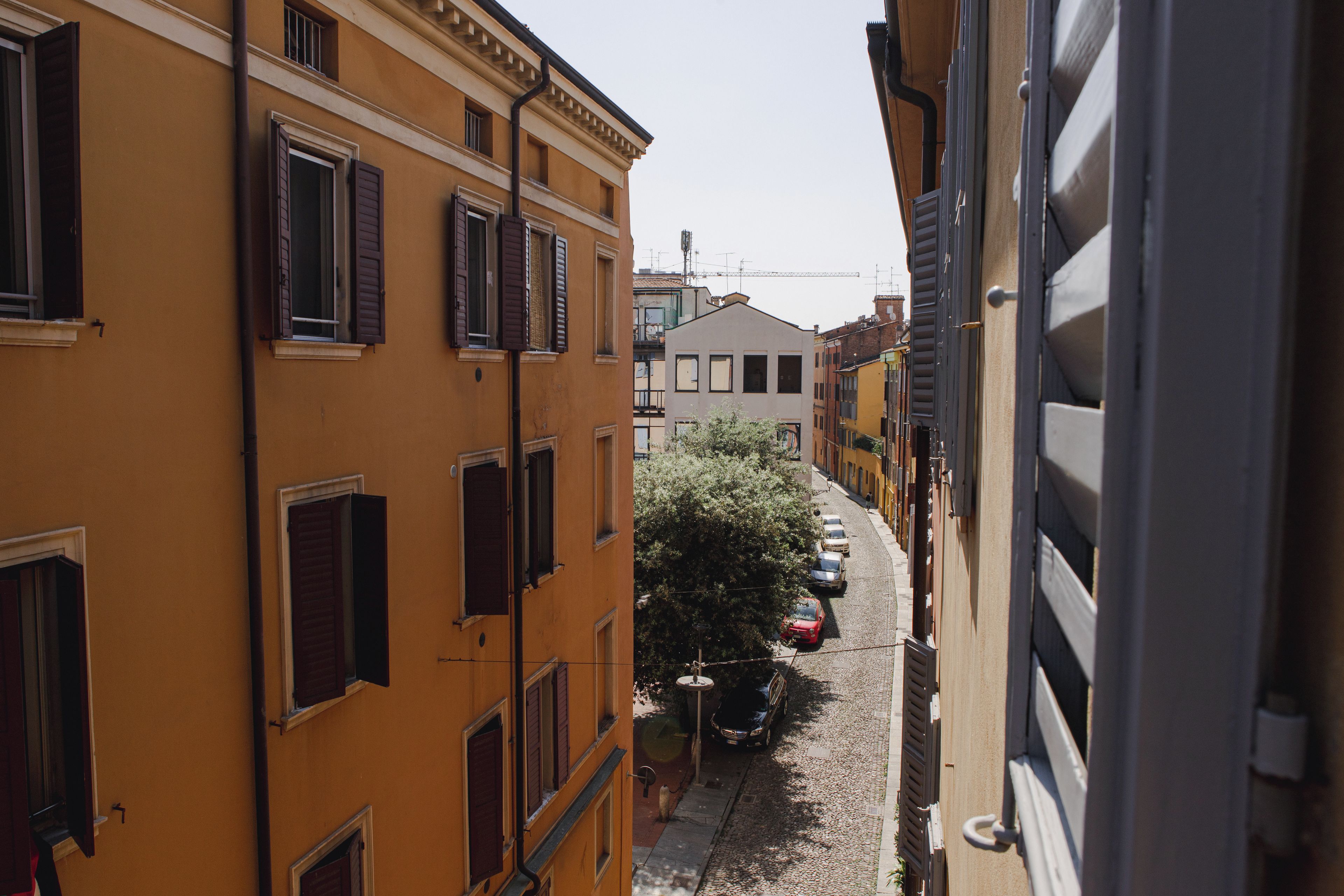 Eine schmale Straße, gesäumt von Gebäuden mit zahlreichen Fenstern und Fensterläden.