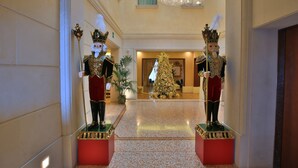 A grand hallway with two ornate statues, a Christmas tree, and a chandelier. - Hotel Rua Frati 48 in San Francesco (Modena)