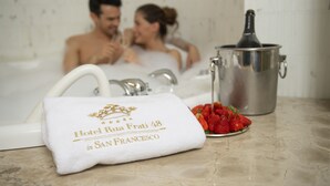 A bathroom with a bathtub, a towel, and a metal container with a bottle. - Hotel Rua Frati 48 in San Francesco (Modena)