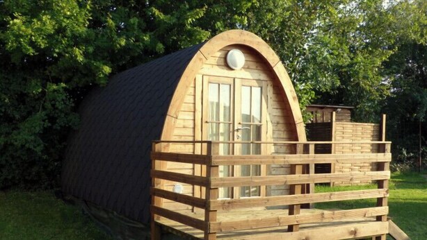 A wooden cabin with a sloped roof, a small porch, and a window. - Camping Le Pontis (Verteillac)