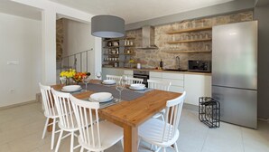 Una cocina moderna con armarios blancos, una mesa de comedor de madera y un horno empotrado.