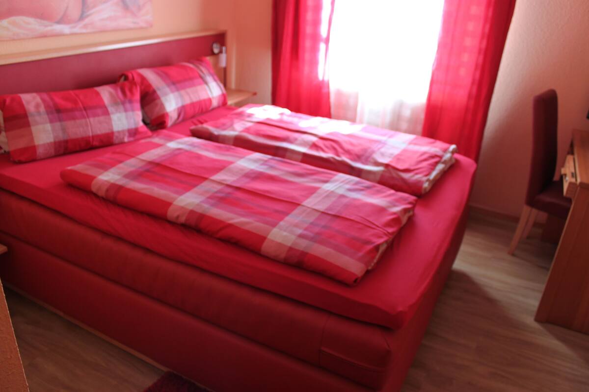 A bed with red bedding and a headboard.