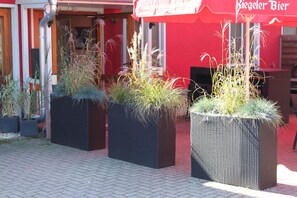 Outdoor planters with plants in front of a building with a red awning. - Hotel Restaurant Hochdorfer Hirschen (Freiburg im Breisgau)