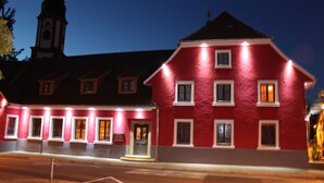 A red building with multiple windows and a clock tower in the background. - Hotel Restaurant Hochdorfer Hirschen (Freiburg im Breisgau)