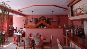 A dining area with a central table and chairs, a bar counter with stools, and a decorative ceiling. - Hotel Restaurant Hochdorfer Hirschen (Freiburg im Breisgau)