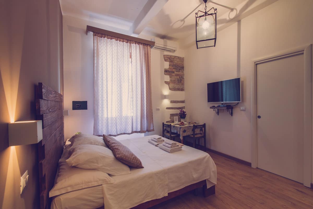 A bedroom with a bed, a desk, a television, and a door.