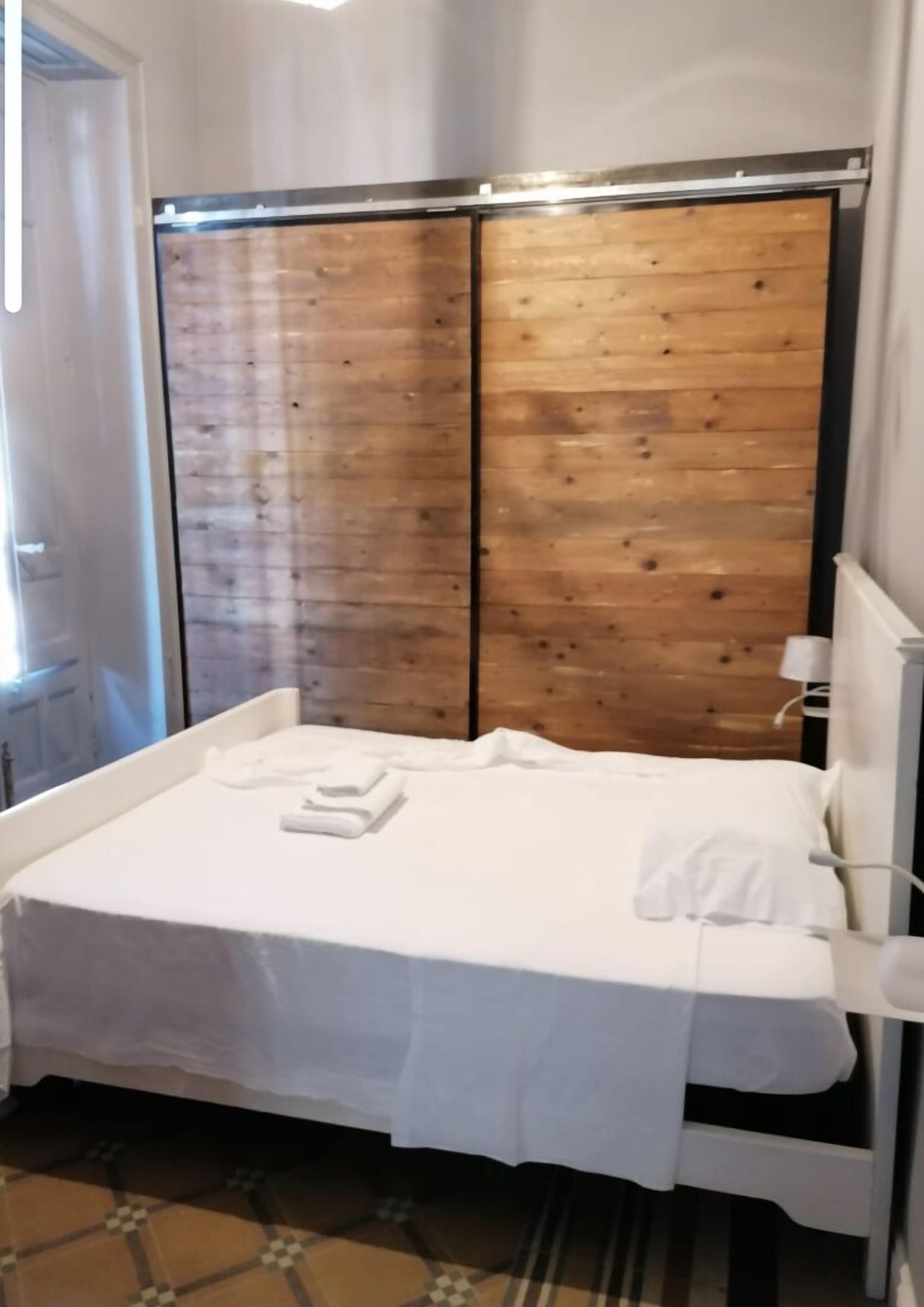 Ein Schlafzimmer mit einem Bett, weißer Bettwäsche, einem Holzschrank und einer Heizung.