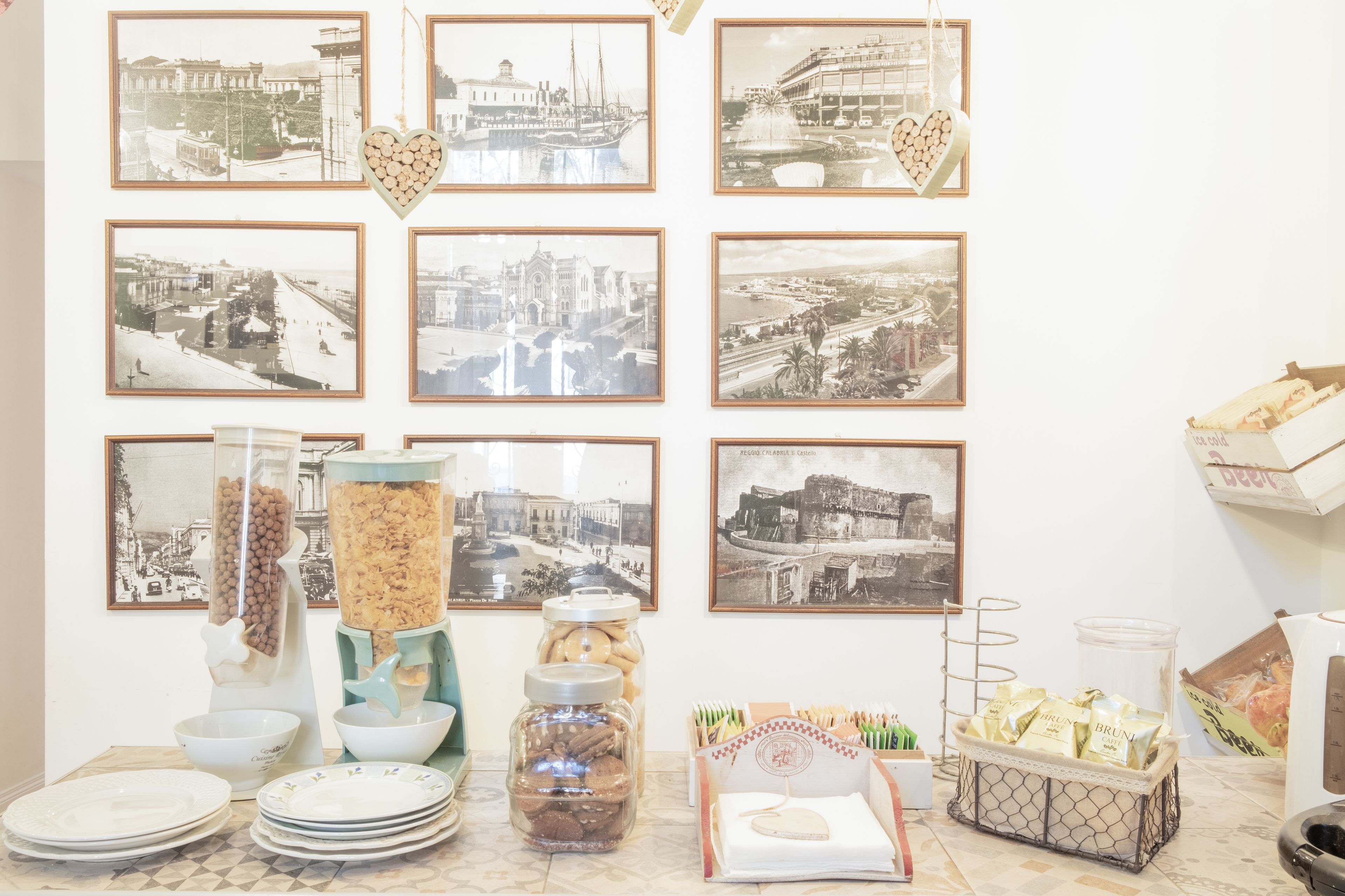 A dining area with a wall of black and white photographs, a buffet with various food items, and a coffee machine.