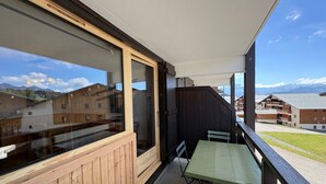 A balcony with a wooden railing, a green table, and a bench. - 2-room apartment with parking in Les Saisies, 4 people, balcony, fully equipped (Les Saisies)