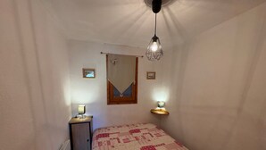 A bedroom with a bed, bedside lamps, a window with a curtain, and a wall-mounted mirror. - 2-room apartment with parking in Les Saisies, 4 people, balcony, fully equipped (Les Saisies)