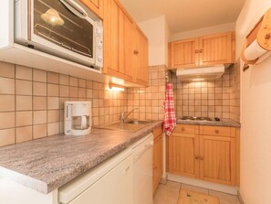 A compact kitchen with wooden cabinets, a microwave, a coffee maker, and a tiled backsplash. - Cozy 2-room apartment for 6, near slopes with south-facing balcony in La Salle-les-Alpes (Serre Chevalier)
