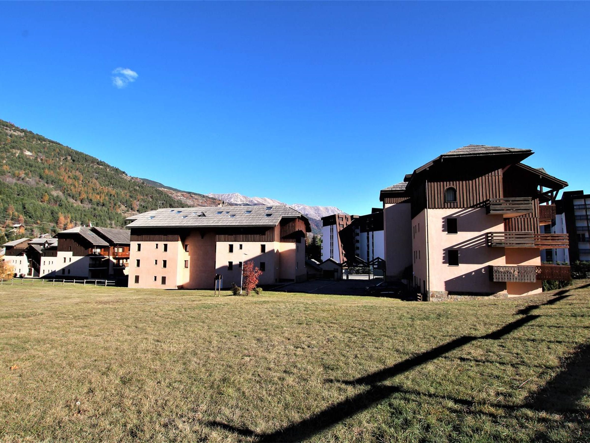 A building with multiple floors, a flat roof, and a large open grassy area in front.