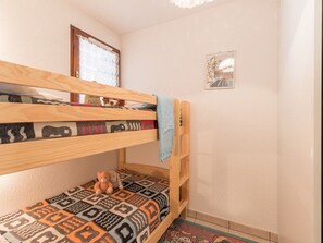 Ein Stockbett mit einem gemusterten Bettbezug und einem Teddybären auf der Unterliege.