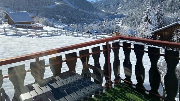 A snowy mountain landscape with a wooden deck and railing. - Cozy studio with south-facing balcony and parking (Châtel)
