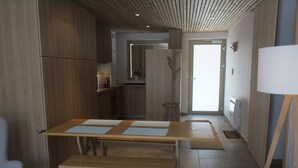 A modern kitchen with wooden cabinets, a dining table with benches, and a view of the adjacent living area. - Comfortable apartment in Châtel with balcony for 4 pers. (Châtel)
