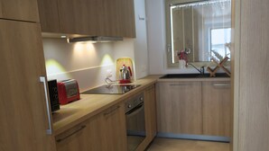 A modern kitchen with wooden cabinets, a toaster, a kettle, and a dishwasher. - Comfortable apartment in Châtel with balcony for 4 pers. (Châtel)
