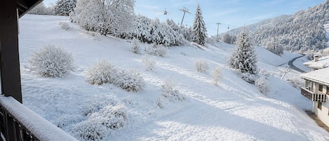 A snow-covered landscape with a wooden balcony overlooking a snowy slope.