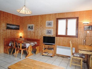Um quarto acolhedor de madeira com uma mesa de jantar, cadeiras, uma televisão e uma janela.