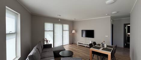 Una sala moderna con un sofá, una mesa de comedor y un televisor de pantalla plana.