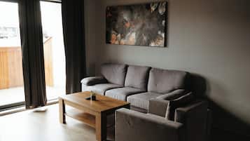 Un salon moderne avec un canapé gris, une table basse en bois et un tableau accroché au mur.