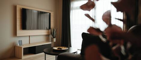 Un salon moderne avec un téléviseur à écran plat fixé au mur, une table basse ronde et un canapé foncé.