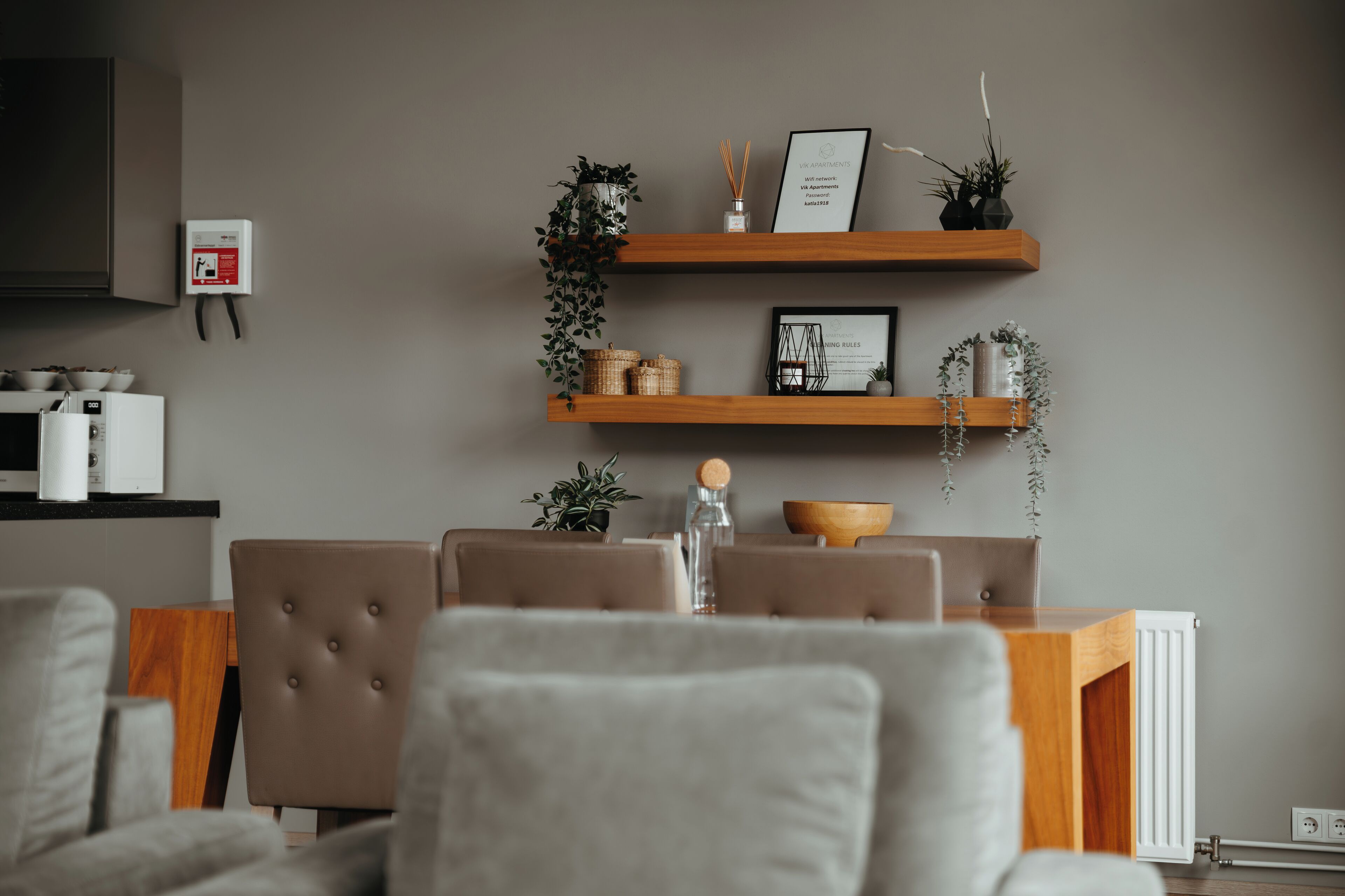 A modern living room with a dining area, featuring a sofa, chairs, a coffee table, and a kitchen area with a refrigerator and cabinets.