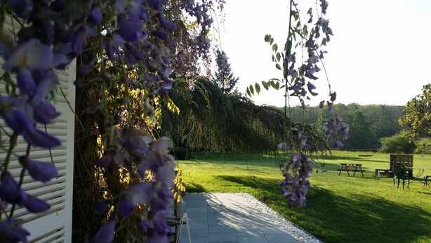 A garden with a patio area, a wooden bench, and a picnic table. - Chambres d'hotes Maison Prairie Bonheur (Magny-les-Hameaux)